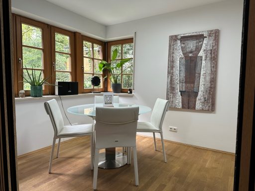 Moderner Essbereich mit Glas-Tisch, weißen Stühlen und großer Fensterfront.