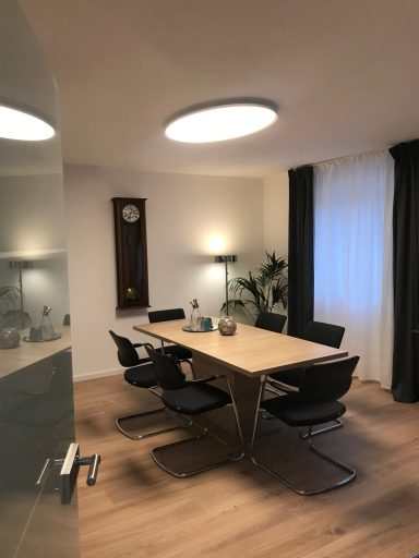 Moderne Besprechungsraum mit Tisch, Stühlen, Pflanzen und Uhr an der Wand.