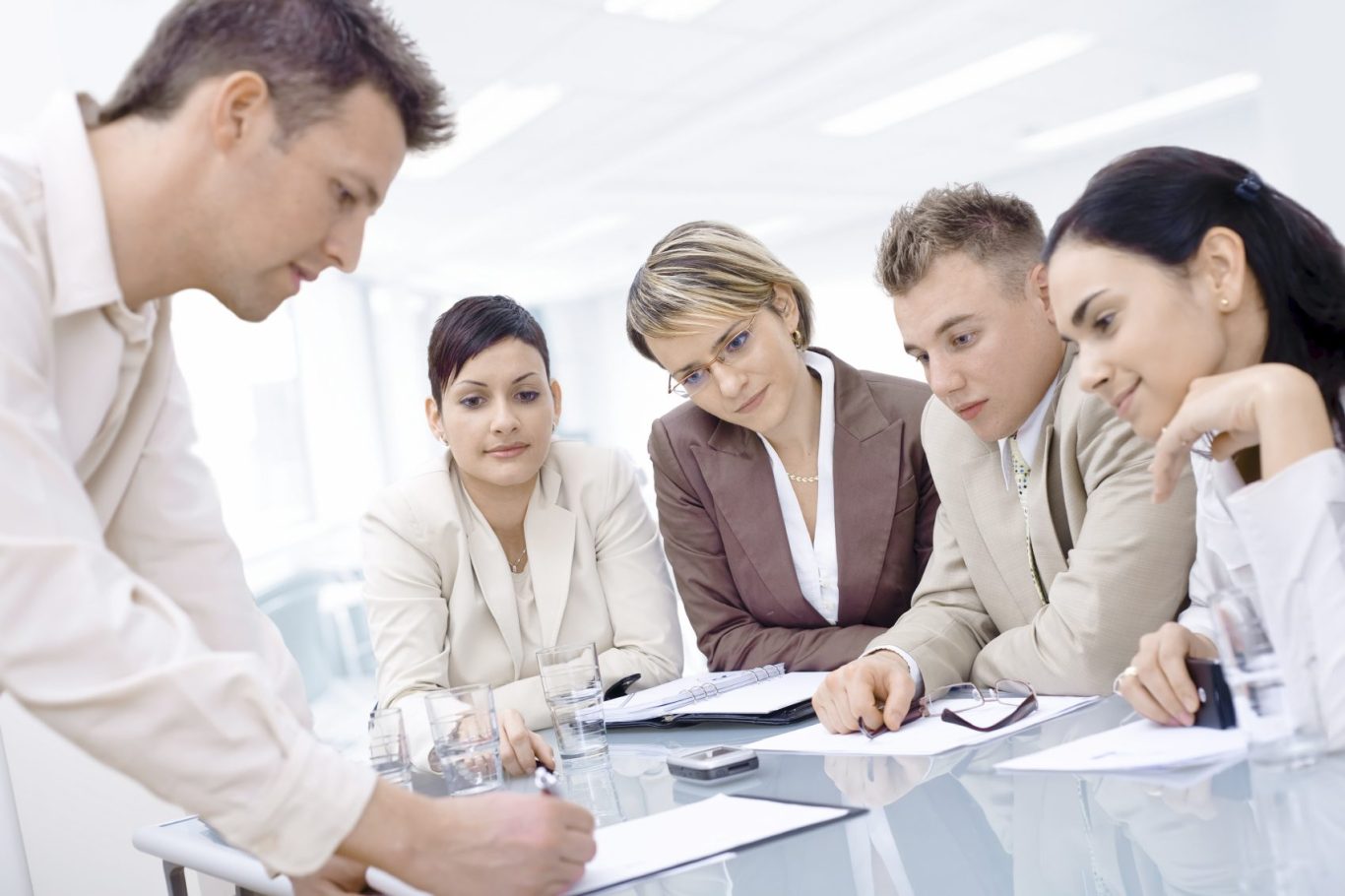 Gruppendiskussion in einem modernen Büro mit fünf Personen in formeller Kleidung.