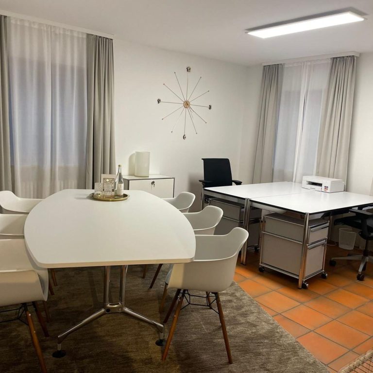 Büro Grünwald Arbeitsplatz 25qm Ein Schreibtisch mit Laptop, Stuhl, Lampe und einem kleinen Pflanzenarrangement.