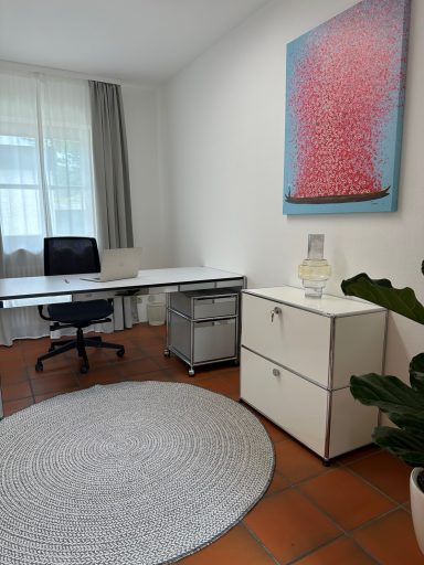 Helles Büro mit Schreibtisch, Stuhl, Aufbewahrungsschrank und Pflanzen. Kunstwerk an der Wand.