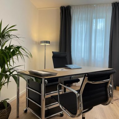 Modernes Büro mit Schreibtisch, Stuhl, Pflanzen und Fenster mit Vorhängen.