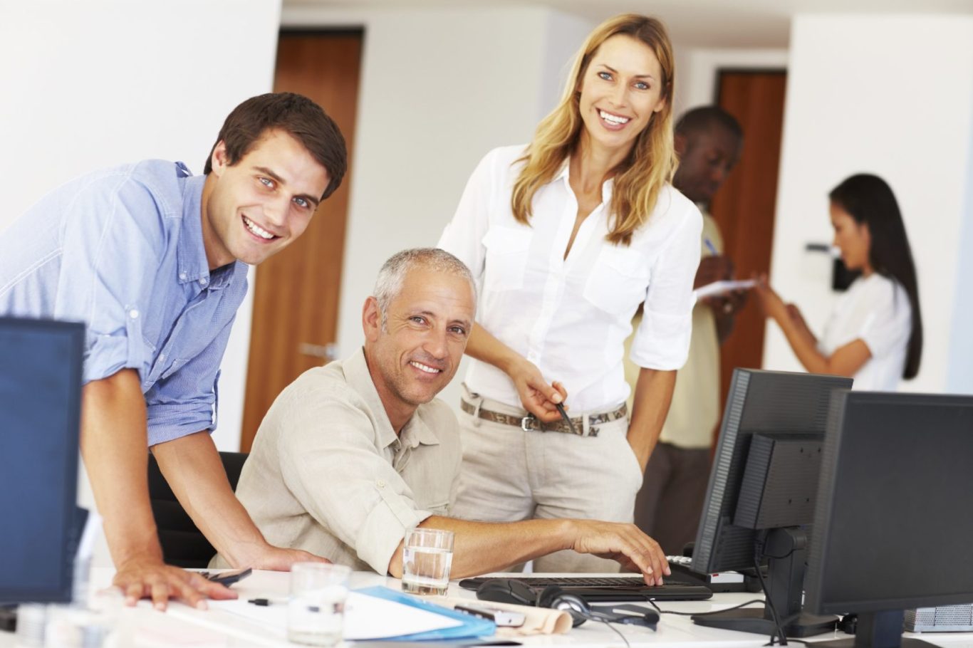 Gruppe von Menschen in einem modernen Büro, die an Computern arbeiten und kommunizieren.