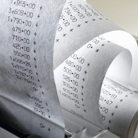 Endloser Papierstreifen mit gedruckten Zahlungen und Summen aus einem Drucker.